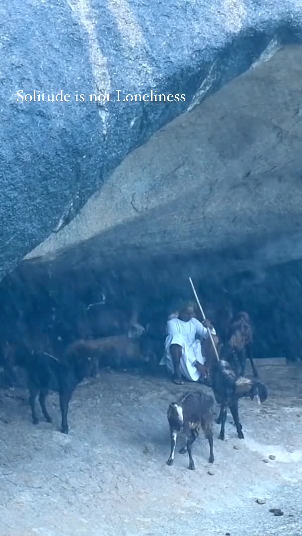 A herder with goats under a rock shelter